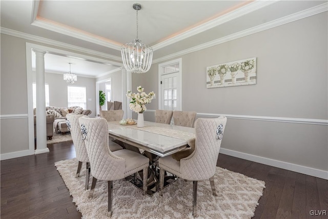 dining area featuring dark wood-type flooring, a raised ceiling, ornamental molding, and an inviting chandelier