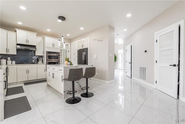 kitchen with decorative backsplash, fridge, hanging light fixtures, white cabinets, and a center island