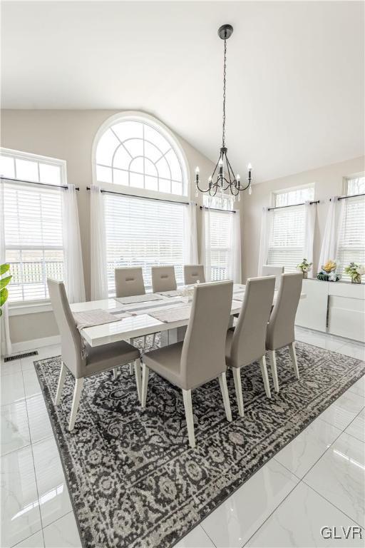 dining space with vaulted ceiling and an inviting chandelier