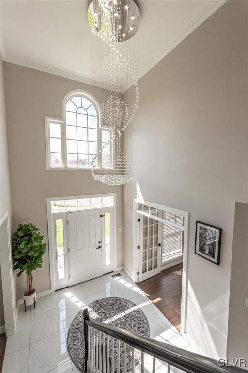 foyer with a chandelier, crown molding, and a towering ceiling