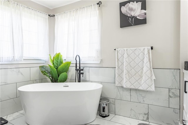 bathroom with tile walls, plenty of natural light, and a bathing tub