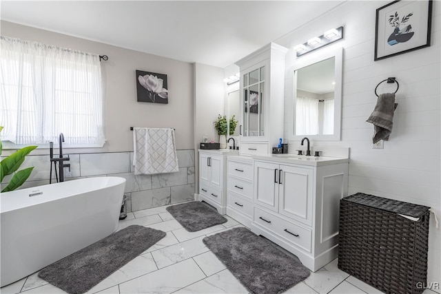 bathroom featuring a tub, vanity, and tile walls