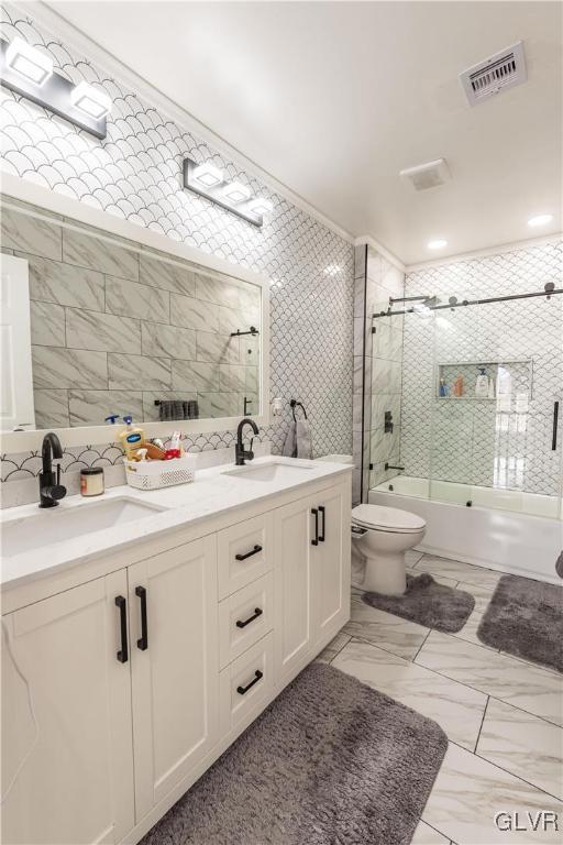 full bathroom featuring toilet, bath / shower combo with glass door, tile walls, and backsplash