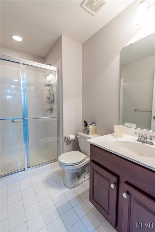 bathroom with toilet, vanity, tile patterned flooring, and an enclosed shower