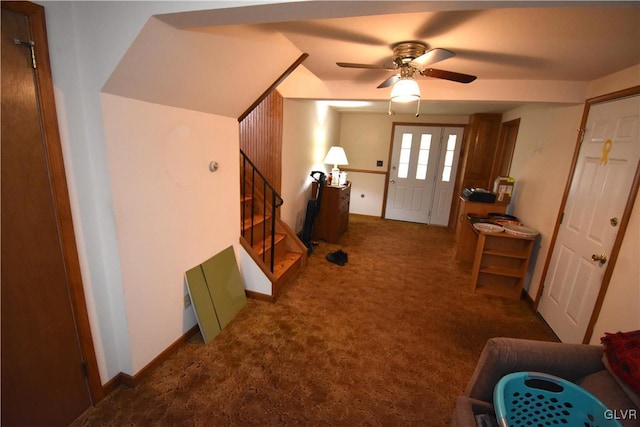 foyer entrance featuring ceiling fan and dark colored carpet