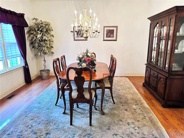 dining area featuring wood-type flooring and a notable chandelier