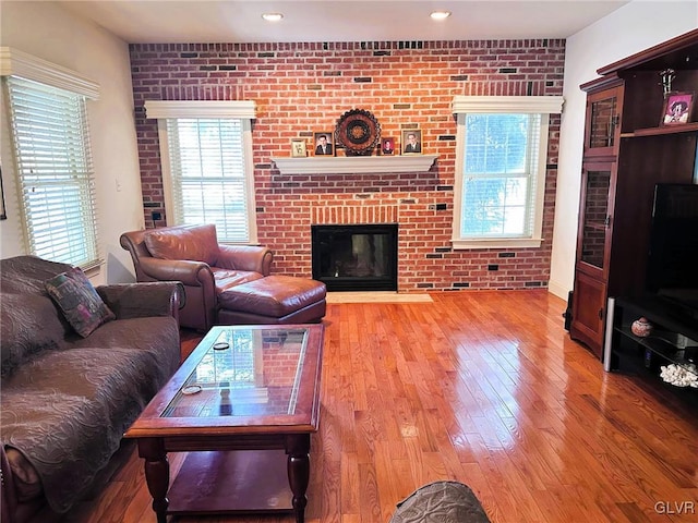 living room with brick wall, a fireplace, and wood-type flooring