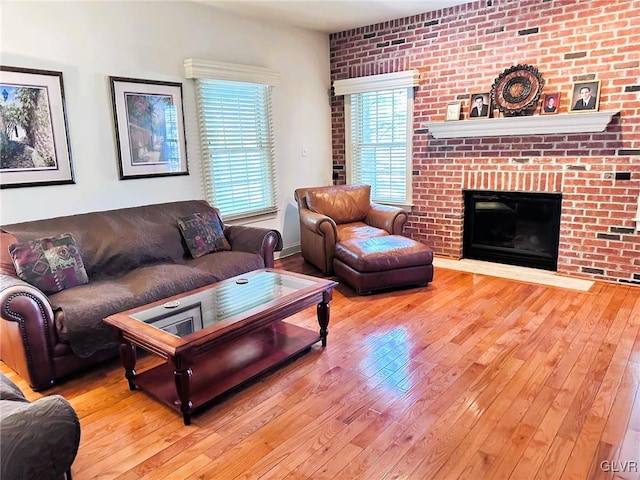 living room with a brick fireplace, light hardwood / wood-style floors, and brick wall