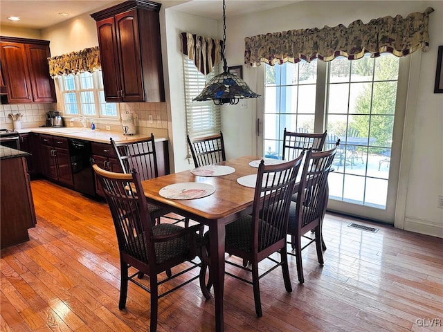 dining space featuring a healthy amount of sunlight, sink, and light hardwood / wood-style flooring