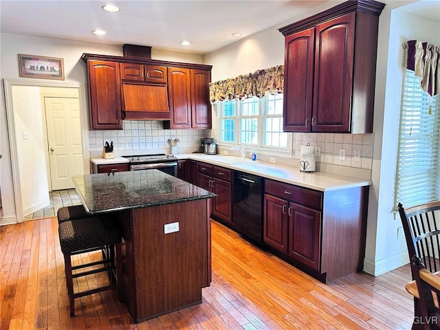 kitchen featuring a center island, black dishwasher, a kitchen breakfast bar, light wood-type flooring, and stainless steel electric range