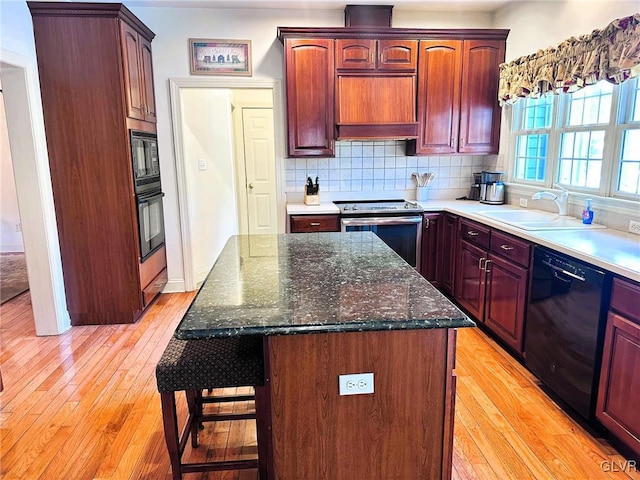 kitchen featuring black appliances, decorative backsplash, light hardwood / wood-style floors, and a center island