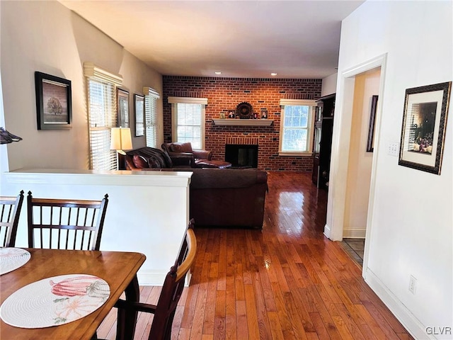 living room featuring dark wood-type flooring, brick wall, and a fireplace