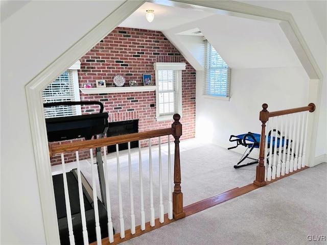 interior space with carpet floors, a brick fireplace, brick wall, and lofted ceiling