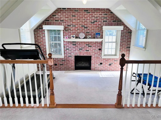 living room with lofted ceiling, a brick fireplace, brick wall, and carpet flooring