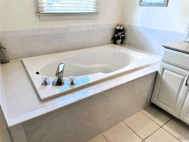 bathroom with tile patterned floors, vanity, and a relaxing tiled tub