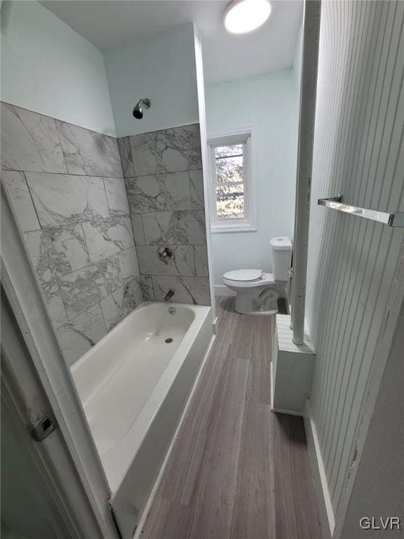 bathroom with toilet, tiled shower / bath, and wood-type flooring