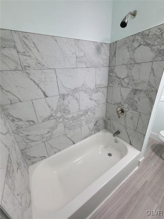 bathroom with shower / bathtub combination, wood-type flooring, and toilet