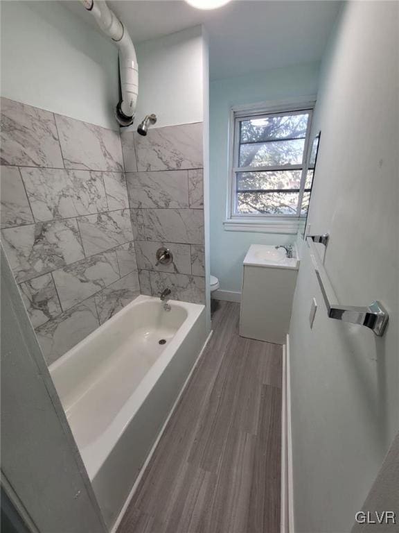 full bathroom with toilet, tiled shower / bath combo, hardwood / wood-style floors, and vanity