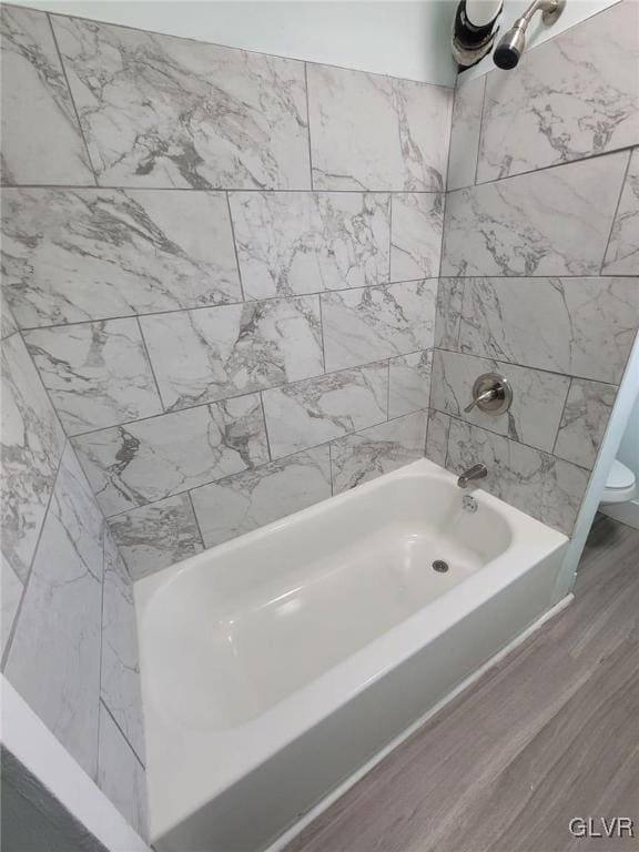 bathroom featuring toilet, tiled shower / bath, and hardwood / wood-style flooring