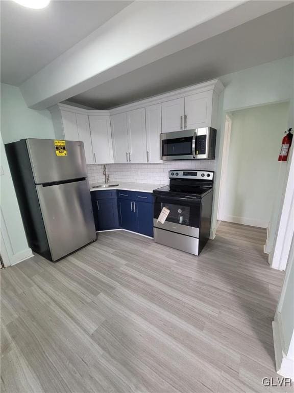 kitchen featuring white cabinets, appliances with stainless steel finishes, light hardwood / wood-style floors, blue cabinetry, and sink