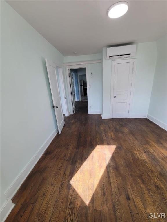 empty room with dark wood-type flooring and a wall mounted AC