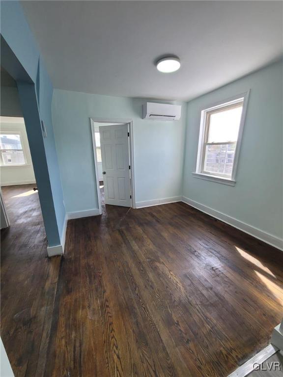 spare room with dark wood-type flooring and a wall mounted air conditioner