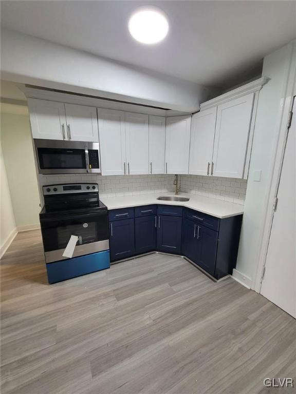 kitchen with white cabinets, decorative backsplash, sink, and stainless steel appliances