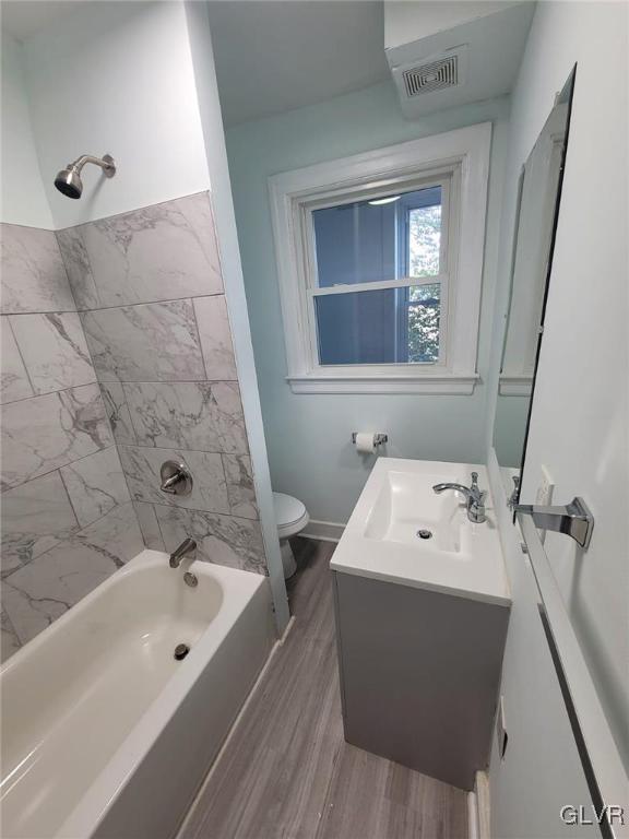 full bathroom with wood-type flooring, toilet, vanity, and tiled shower / bath combo