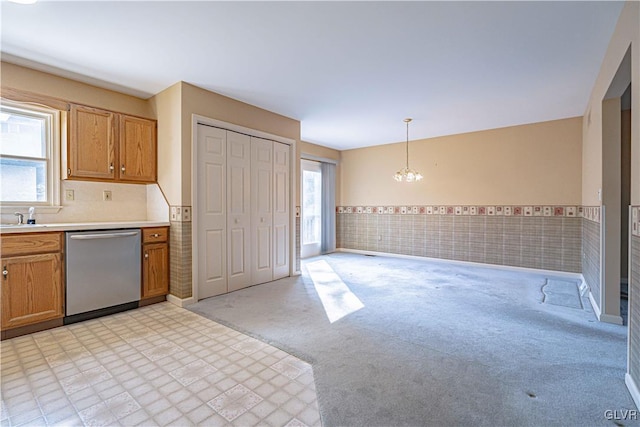 kitchen with decorative light fixtures, tile walls, a chandelier, light colored carpet, and stainless steel dishwasher