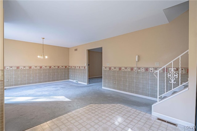 unfurnished room featuring tile walls, a chandelier, and carpet flooring