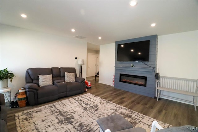 living room with dark wood-type flooring and a large fireplace