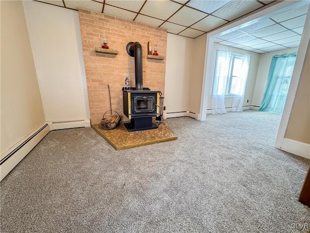 unfurnished living room with a paneled ceiling, a wood stove, and carpet floors