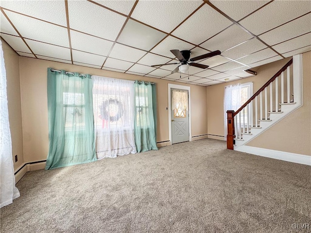 unfurnished living room featuring ceiling fan, baseboard heating, a drop ceiling, and carpet flooring