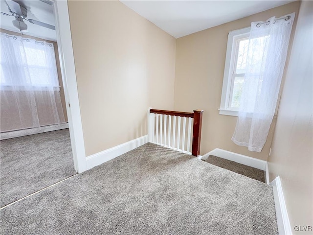 empty room with carpet, a baseboard heating unit, and ceiling fan