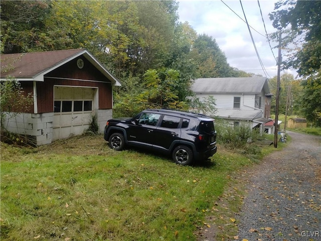 view of side of property with a garage, an outbuilding, and a lawn