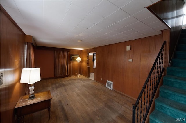 corridor with hardwood / wood-style flooring, a wall mounted AC, and wooden walls