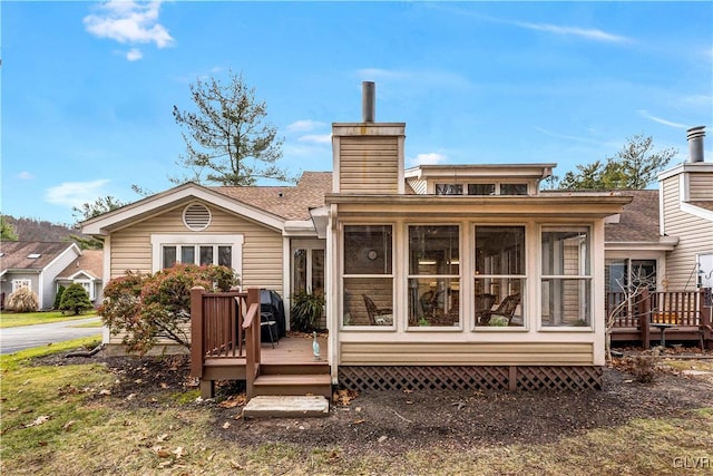 rear view of house with a wooden deck and a sunroom