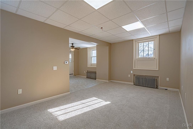 carpeted spare room with ceiling fan, a drop ceiling, and radiator heating unit