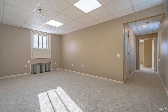 carpeted empty room with radiator and a paneled ceiling