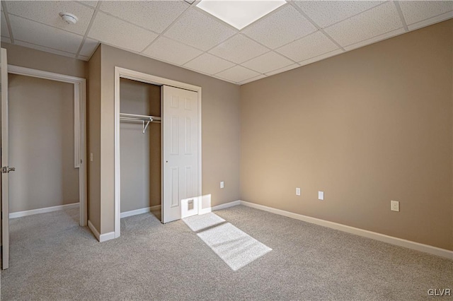 unfurnished bedroom featuring light carpet, a closet, and a drop ceiling