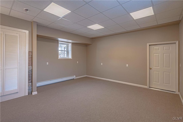 basement featuring carpet floors, a drop ceiling, and a baseboard heating unit