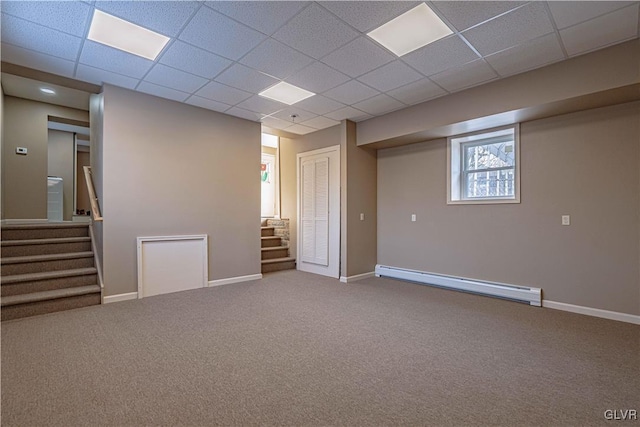 basement featuring a drop ceiling, a baseboard heating unit, and carpet