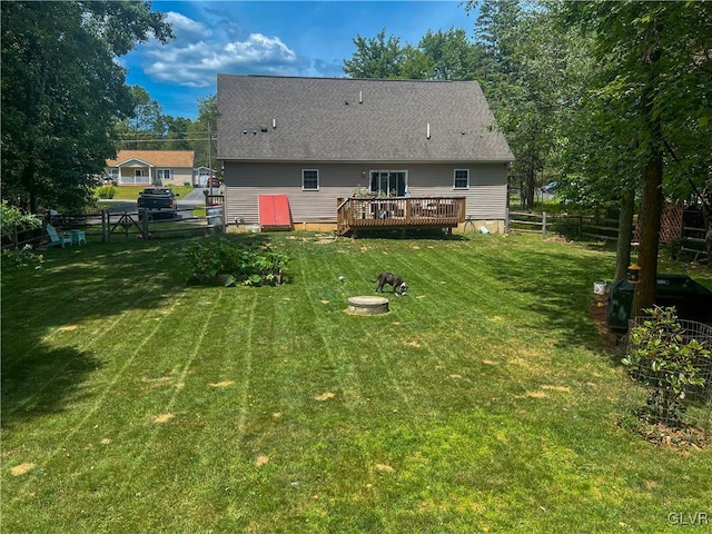 rear view of property with a wooden deck, an outdoor fire pit, and a lawn