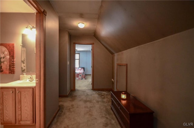 corridor with lofted ceiling, light colored carpet, and sink