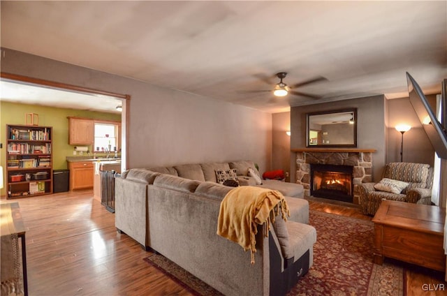 living room with ceiling fan, a fireplace, and hardwood / wood-style floors