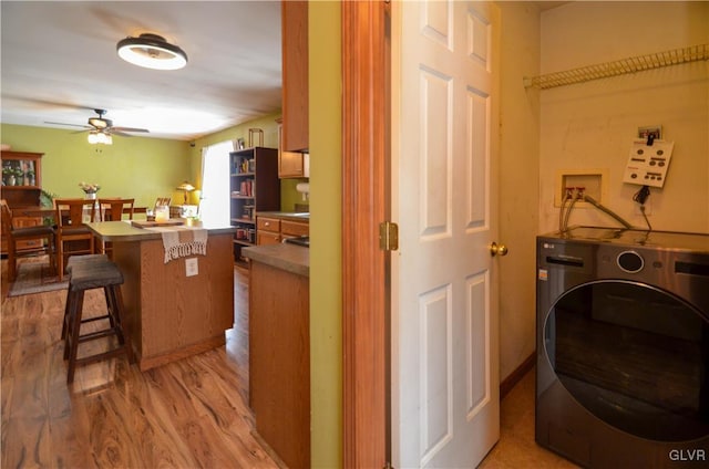 laundry area with ceiling fan, washer / clothes dryer, and light hardwood / wood-style flooring