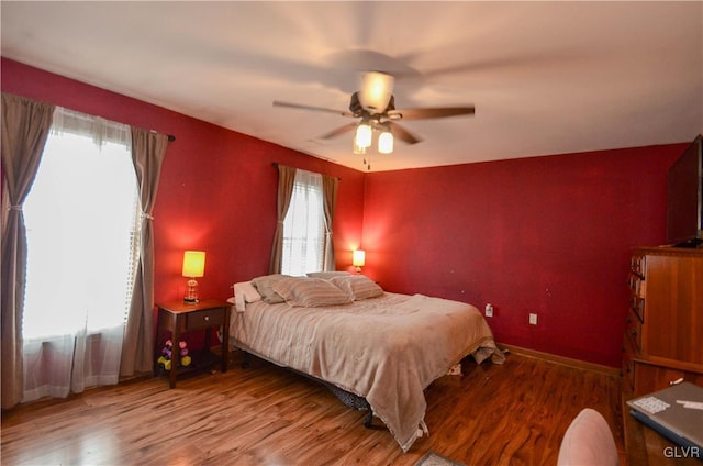 bedroom featuring ceiling fan, hardwood / wood-style flooring, and multiple windows