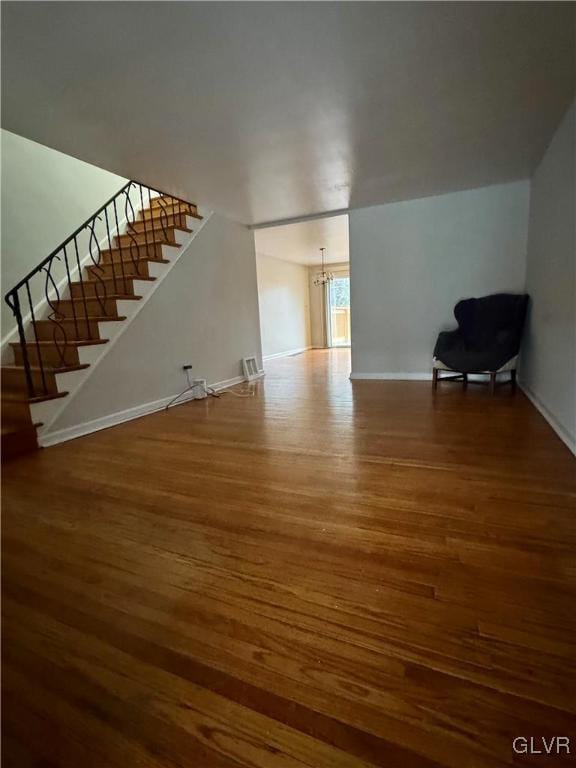 unfurnished living room with wood-type flooring and an inviting chandelier