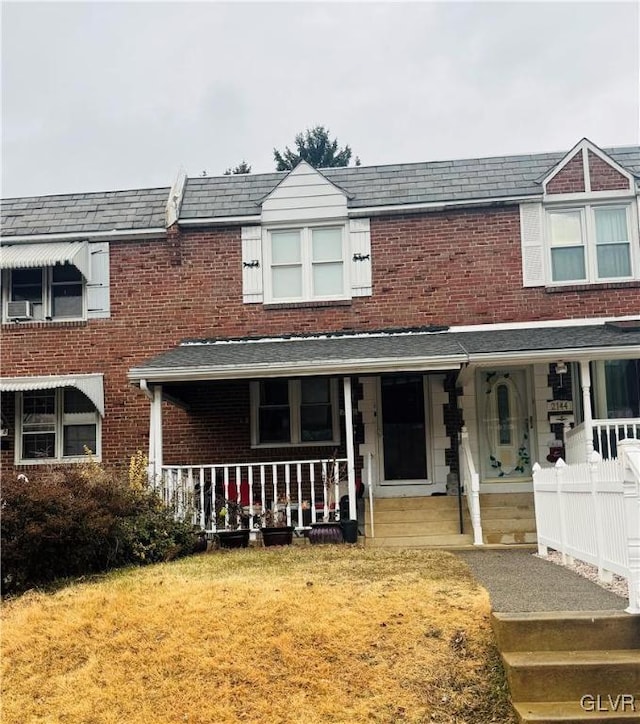 view of property featuring covered porch and a front yard