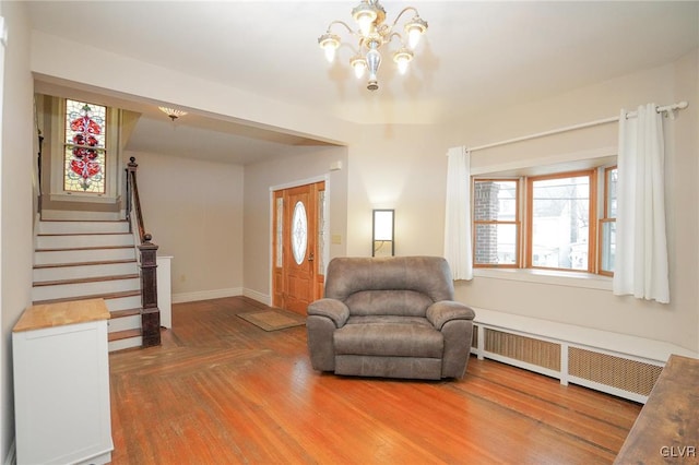 living area featuring radiator, a notable chandelier, a healthy amount of sunlight, and hardwood / wood-style floors